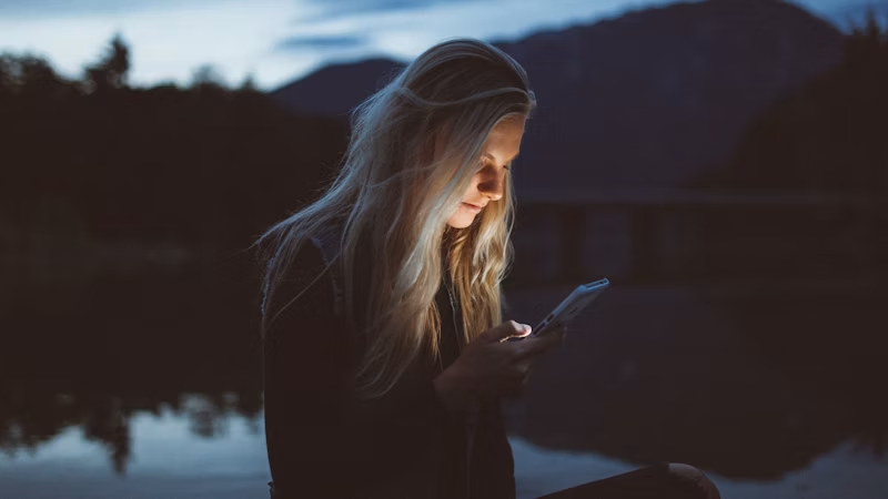 水辺でスマホを見る女性